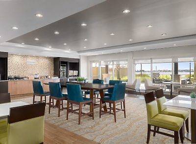 Modern hotel dining area with seating and large windows overlooking outdoor space