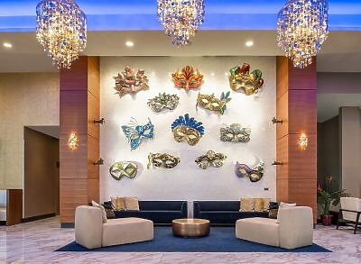 Decorative mask wall art in hotel lobby with seating area and chandeliers