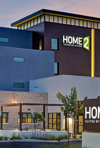 Modern hotel exterior with illuminated signage and landscaping