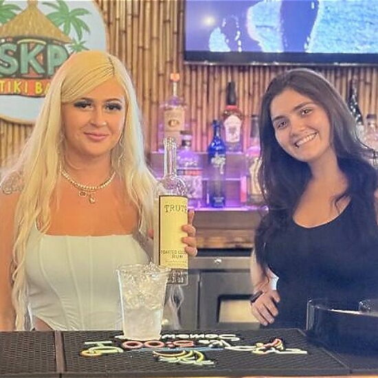 Two welcoming bar-team members behind the counter at Hidden Oasis Tiki Bar
