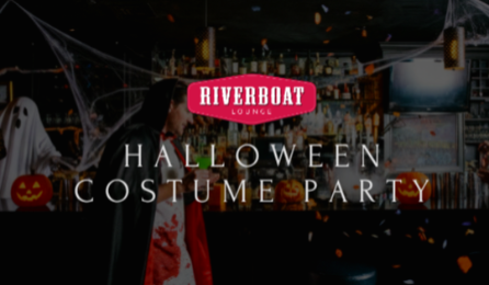 Halloween-themed party with guests in costumes, decorated bar area featuring skeletons and festive decor.