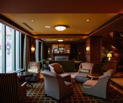 Hotel Julien Dubuque lobby featuring plush armchairs, a decorative fireplace, and large windows for natural light.