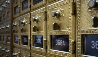 Close-up of ornate golden mailboxes with numbered slots, showcasing intricate designs and shiny metal finishes.