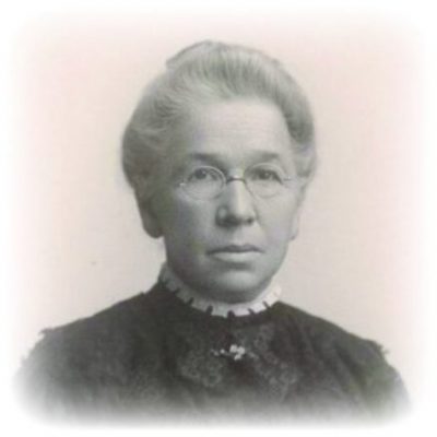 Black-and-white portrait of a woman with glasses, wearing a dark dress and white collar, displaying a serious expression.