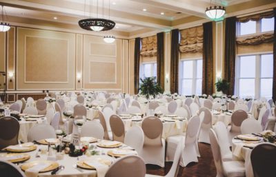 Elegant banquet hall set for an event, featuring round tables with white tablecloths