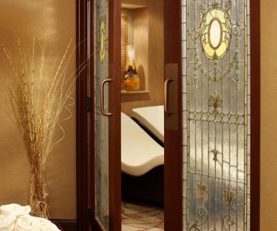 Elegant glass doors leading to a tranquil spa area with soothing decor and plush seating.