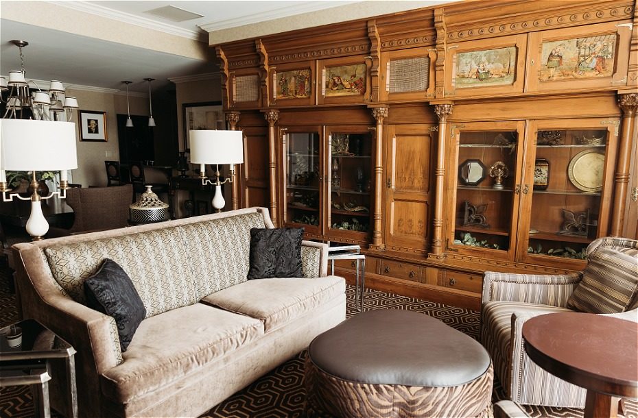 Spacious hotel sitting area with plush sofas, decorative cabinet, and stylish lighting fixtures. Warm, inviting decor.