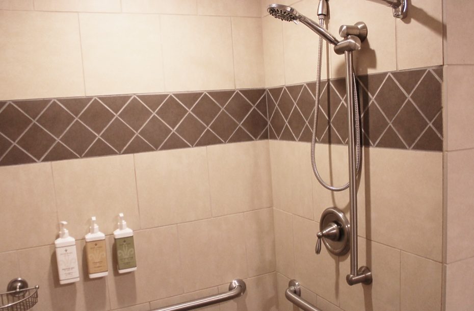 Modern hotel shower with adjustable showerhead, grab bars, and complimentary shampoo and body wash dispensers.