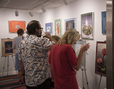 Patrons in the Jac Tilton Memorial student art gallery looking at artwork at the Galena Center for the Arts