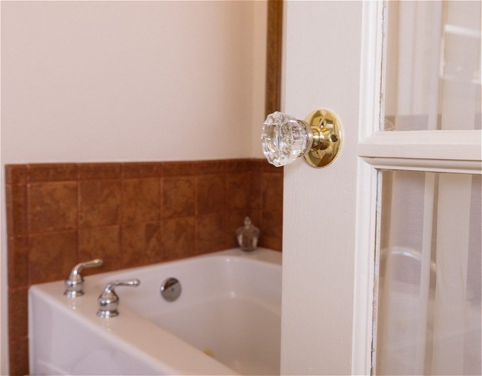 a shot of a bathroom with a door and bathtub