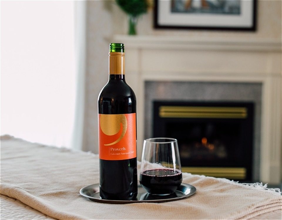 Bottle and glass of wine near fireplace