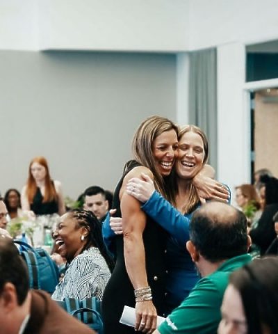 Two women at event hugging and smiling